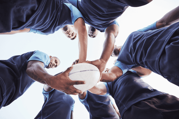 a football team in a huddle, touching a football